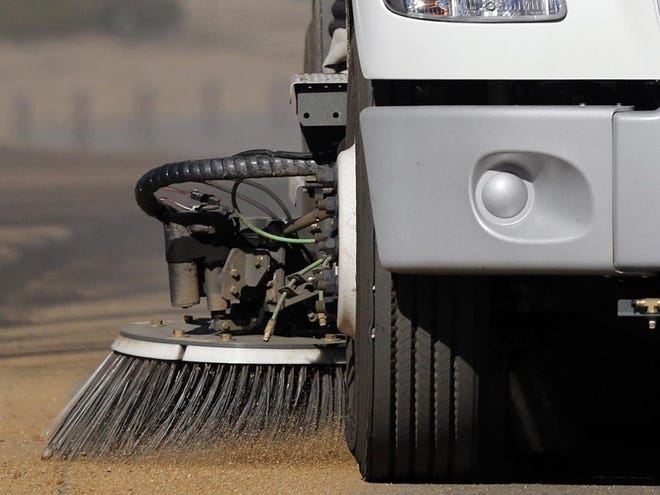 A sweeper truck clears sand. [File staff photo]