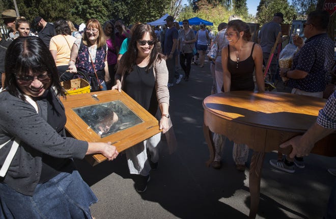 Carrying their purchases through the busy streets of Coburg, Linda Carrasquillo, left, and Joan Hayworth-Liu, center, navigate around Deborah Lee, right, from Chile as they joins thousands of others for the Coburg Antique Fair. [Chris Pietsch/The Register-Guard] - registerguard.com