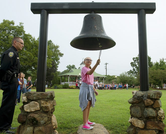 Denton Elementary School fifth-grader Karson Money takes her turn at the ringing of the bell during the 9/11 memorial service at Harrison Park in Denton on Tuesday morning. Denton Police Chief Mark Hicks stands by. [Donnie Roberts/The Dispatch]