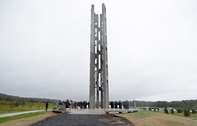 FILE - In this Sept. 9, 2018 file photo, people attending the dedication stand around the 93-foot tall Tower of Voices at the Flight 93 National Memorial in Shanksville, Pa., where the tower contains 40 wind chimes representing the 40 people that perished in the crash of Flight 93 in the terrorist attacks of Sept. 11, 2001. Thousands of victims' relatives, survivors, rescuers and others are expected at Tuesday's Sept 11 Anniversary ceremony at the World Trade Center. President Donald Trump and first lady Melania Trump plan to join an observance at the new Shanksville, tower honoring victims, and Vice President Mike Pence is attending a ceremony at the Pentagon. (AP Photo/Keith Srakocic, Pool, File)