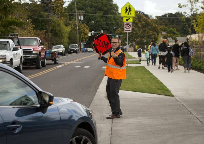 River Road/El Camino del Rio Elementary School Principal Joel Lavin directs traffic at the end of the school day on Tuesday. Lavin works with staff and volunteers to control traffic going in and out of the parking lot along Hilliard Street. [Andy Nelson/The Register-Guard] - registerguard.com
