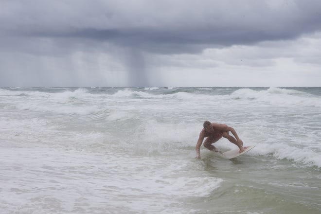 Mike Blanchard skimboards near Russell-Fields Pier as rain pelts the Gulf of Mexico in Panama City Beach on Wednesday. "You don't get surf very often, so you got to get it while you can," he says. [JOSHUA BOUCHER/THE NEWS HERALD]