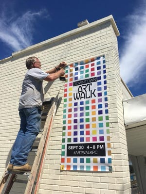 Maxwell Miller hangs an Art Walk sign on the wall at Artisan Enclave in downtown Panama City. The event is 4-8 p.m. Thursday, Sept. 20. [CONTRIBUTED PHOTO]