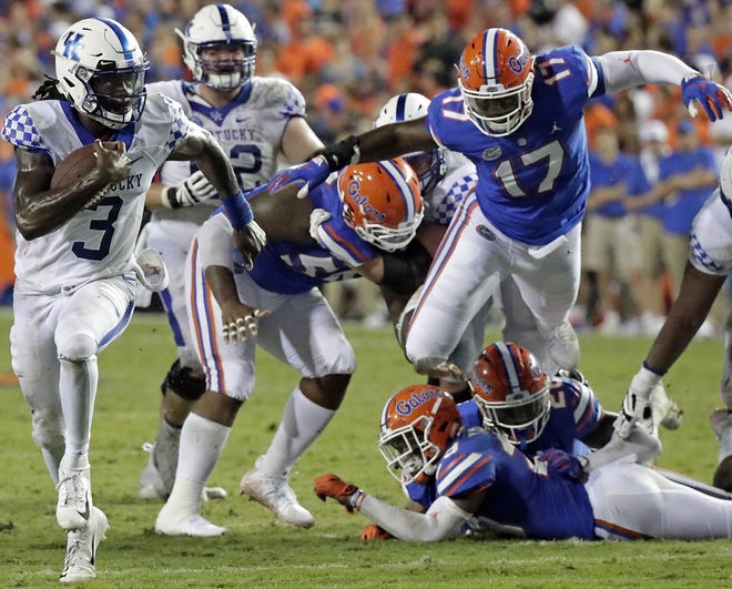 Kentucky quarterback Terry Wilson runs past Florida defensive end Zachary Carter (17) and other defensive players for a 24-yard touchdown during the second half Saturday in Gainesville. [John Raoux/Associated Press]