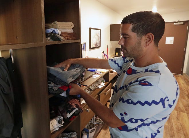 In this Monday, Sept. 10, 2018, photo, Jose Santiago folds clothing in his room at the WoodSpring Suites in Orlando, Fla. Santiago, like many Puerto Rican evacuees, has until Friday to find a place to live. (AP Photo/John Raoux)