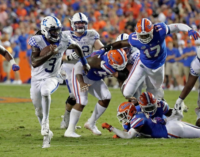 Kentucky quarterback Terry Wilson (3) runs past Florida defensive end Zachary Carter (17) and other Gators for a 24-yard touchdown during the second half of Saturday's game in Gainesville, Fla. [AP Photo/John Raoux]