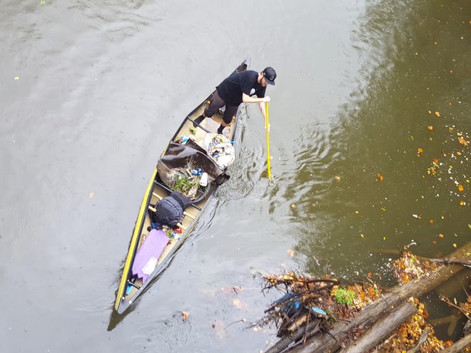 Adam Scott of Loudonville maneuvers a canoe into position to retrieve trash from a logjam along the Mohican River during Saturday’s river cleanup.