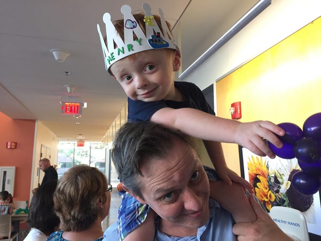 Henry Benson, 4, rides the shoulders of his father, Tim Benson, at a reunion of 4-year-olds who were born premature at Women & Infants Hospital in 2014. The little Benson wears a crown he decorated with stickers and holds the balloon animal that magician Lon Cerel made for him. [The Providence Journal / Donita Naylor]