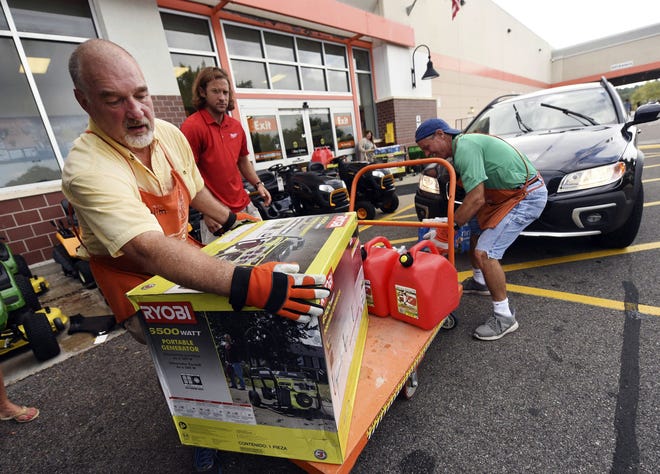 Jim Craig, David Burke and Chris Rayner load generators as people buy supplies at The Home Depot in Wilmington, N.C. [KEN BLEVINS/THE STAR-NEWS]