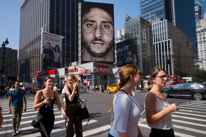 People walk by a Nike advertisement featuring Colin Kaepernick on display, Thursday, Sept. 6, 2018, in New York. (AP Photo/Mark Lennihan)