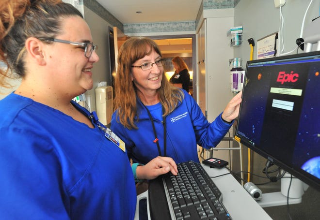 LESLIE RENKEN/JOURNAL STAR Mimi Cofoid, Clinical Informatics Coordinator for UnityPoint Health, right, and CNA Vanessa Malcolm, left, opens up the new Epic medical records system in a patient room at Pekin Hosptial Friday afternoon.
