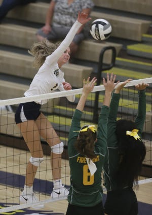 Copley's Katherine Davis spikes the ball over Firestone's Josey Capper and Jakai Polk (right) in the third set Wednesday in Copley. [Mike Cardew/Beacon Journal/Ohio.com]