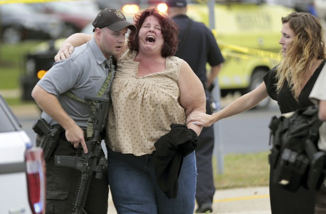 A woman is escorted from the scene of Wedneday's shooting at a software company in Middleton, Wis., a suburb of Madison. [Wisconsin State Journal via AP / Steve Apps]