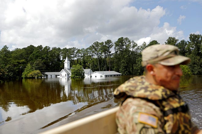 The Presbyterian Church of the Covenant sits flooded as U.S. Army Spc. Daniel Ochoa rides in the back of a high water vehicle while searching for residents to evacuate in the aftermath of Hurricane Florence in Spring Lake on Monday. [AP Photo/David Goldman]