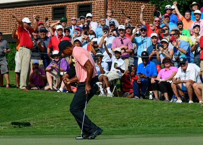 Tiger Woods drains an eagle putt on the 18th green during the first round of the Tour Championship on Thursday in Atlanta. [John Amis/The Associated Press]