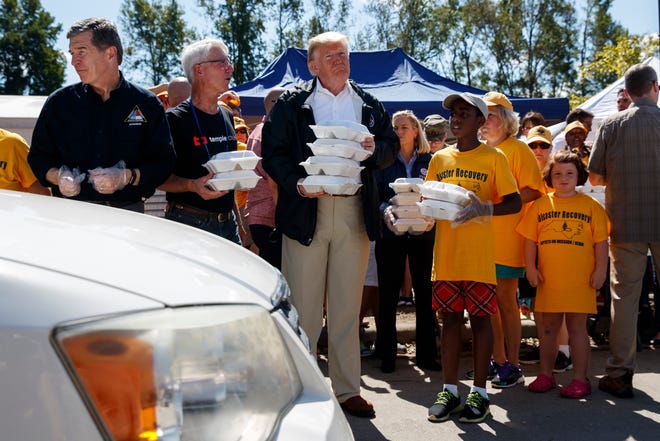 President Donald Trump hands out prepackaged meals to people in cars at Temple Baptist Church in an area impacted by Hurricane Florence, Wednesday, Sept. 19, 2018, in New Bern, N.C.