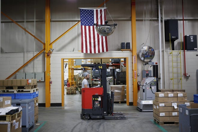 An American flag hangs above a worker operating a forklift at the Stihl Inc. manufacturing facility in Virginia Beach, Virginia, in this Jan. 11 file photo. [LUKE SHARRETT/BLOOMBERG]
