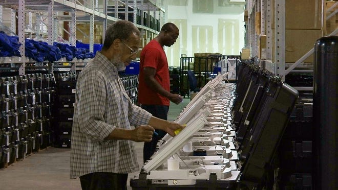 FILE - In this Sept. 22, 2016, file photo, employees of the Fulton County Election Preparation Center in Atlanta test electronic voting machines. Voting integrity advocates had argued Georgia's electronic voting machines are unreliable and vulnerable to hacking, but a federal judge says forcing the state to change its system to paper ballots before the midterm elections is too risky. (AP Photo/Alex Sanz, File)