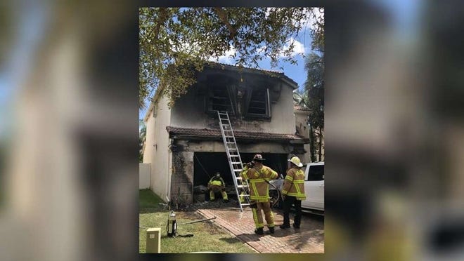 Palm Beach County firefighters inspect damage at the scene of a house fire Friday in suburban Lake Worth (Photo by Palm Beach County Fire Rescue)