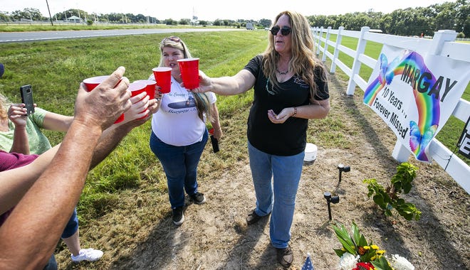 Karisa Beasley, left and Sue Nassivera lead a small group of friends in a toast with Mountain Dew and Skittles at a memorial Sunday near the site of the 2008 crash where Margay Schee died after a semi driver hit the back of her school bus on U.S. 301 near Citra. "She will never be forgotten and we miss you," Beasley said. [Doug Engle/Staff photographer]