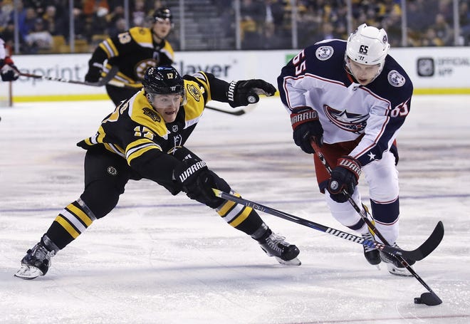 Boston Bruins forward Ryan Donato, left, tries to poke the puck away from Columbus Blue Jackets defenseman Markus Nutivaara (65) during the second period of an NHL hockey game in Boston, Monday, March 19, 2018. (AP Photo/Charles Krupa)