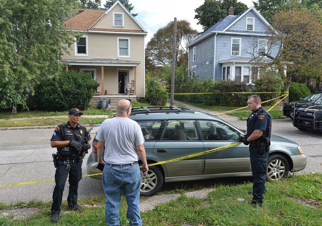 Erie Bureau of Police officers Tom Lenox, at left, and Brian Wisniewski, at right, talk with Jonathan Reck, center, near the scene of a fatal stabbing on Monday. Earlier in the day, police found a woman dead in the home in the background, at left, located in the 2500 block of Wallace Street. Reck, 53, of Erie, told police that he was a friend of one of the occupants of the house. [CHRISTOPHER MILLETTE/ERIE TIMES-NEWS]