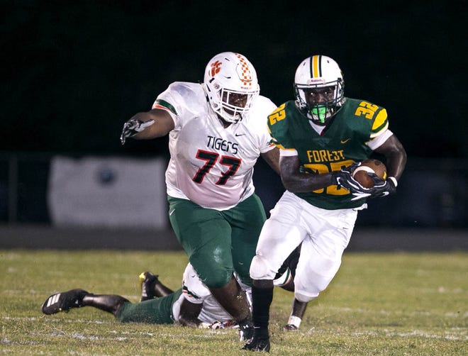 Jones High School's #77 Bryan Moore goes after Forest's (32) Robert Wesley, Friday, September 21, 2018 at Forest High School in Ocala, Florida. The Fightin' Tigers beat the Wildcats 60-0. [Cyndi Chambers/Ocala Star Banner Correspondent] 2018