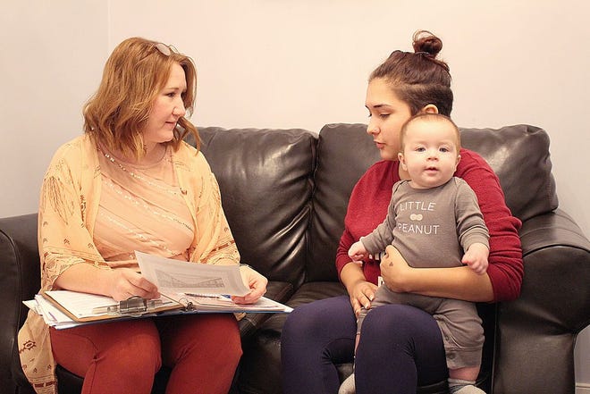 Hope Pregnancy Center client coach Alesha Kendrick, left, goes over some paperwork with Dayle Rangel and her 8-month-old son, Steven Colvin, during a visit.