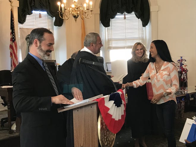 Rayfi Guzman receives her naturalization certificate as she shakes hands with U.S. District Court Chief Judge Jose L. Linares during the ceremony. [LISA RYAN / STAFF PHOTOJOURNALIST]