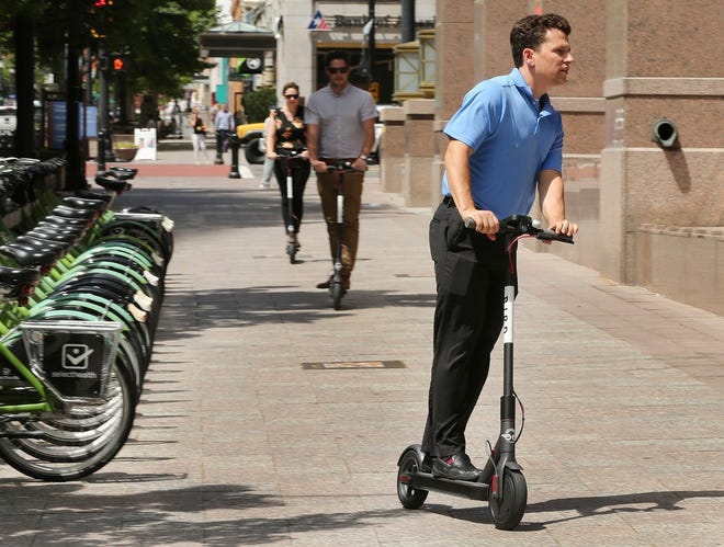 Mark Rodgers rides a Bird electric scooter in Salt Lake City on Thursday, June 28, 2018. The electric scooters just made their first appearance with 100 of them distributed in downtown. The city of Gainesville is in the process of giving permits to several companies to bring its first dockless rental program into the city. [Jeffrey D. Allred/The Deseret News via AP]