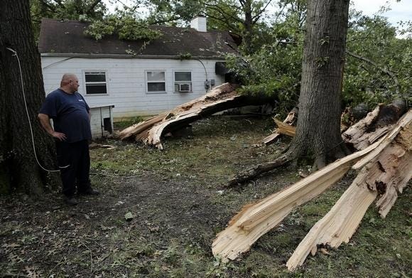 Travis Burns of West Jefferson looks at the massive oak tree limbs brought down by a tornado at the house being rented by his stepson Codey Boyer on South Hampton Road in Columbus. (GateHouse Media Ohio / Jonathan Quilter, Colmbus Dispatch)