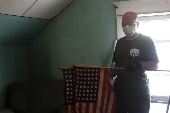 A Home Depot Foundation volunteer finds two American flags inside Eason's home during a cleanup and repair sponsored by the city of Savannah and Home Depot. [Brittini Ray/ savannahnow.com]
