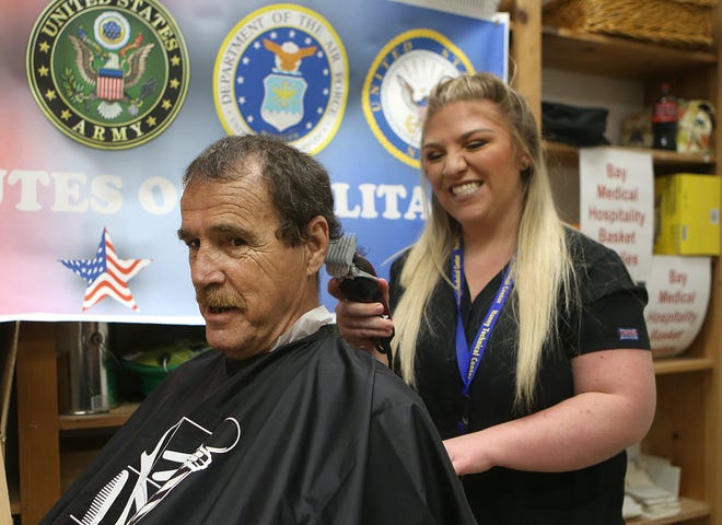 Meghan Rodriguez gives Army veteran Tom a haircut. Homeless veterans received a free meal, haircuts, hygiene products and other essential items on Thursday during the annual Veterans Stand Down at First Baptist Church. [PATTI BLAKE/THE NEWS HERALD]