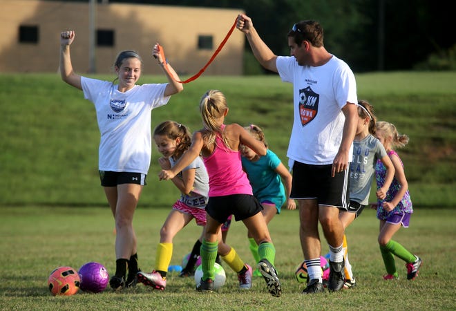 From left, Sarah Drennan and Tyler Deaton work with young soccer players at a Kings Mountain Soccer Club meeting on Thursday. [Brittany Randolph/The Star]