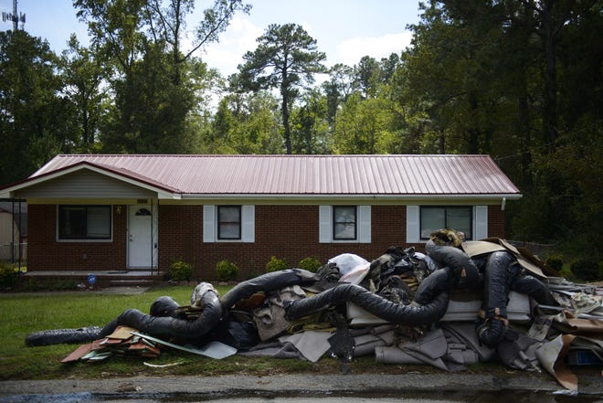 On Friday, debris from a flooded home sits on the curb of Louise Circle, where many house have been abandoned. [Melissa Sue Gerrits/The Fayetteville Observer]