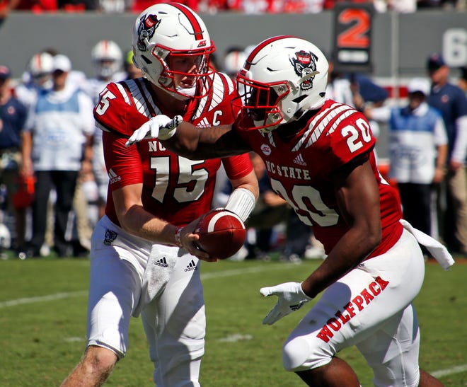 North Carolina State quarterback Ryan Finley hands off to Ricky Person Jr. during the first half against Virginia in Raleigh on Saturday. N.C. State won 35-21. [AP Photo/Chris Seward]