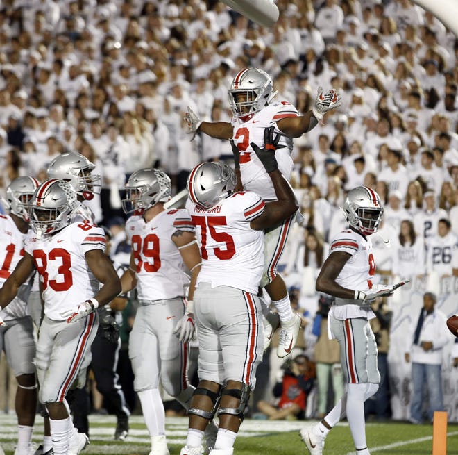Ohio State's J.K. Dobbins (2) is lifted up by teammate Thayer Munford (75) after scoring against Penn State during the second half in State College, Pa. on Saturday. Ohio State won 27-26. [CHRIS KNIGHT/THE ASSOCIATED PRESS]