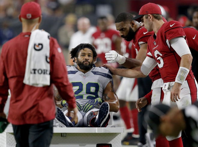 Seattle Seahawks defensive back Earl Thomas (29) is greeted by Arizona Cardinals players as he leaves the field after breaking his leg during the second half of Sunday's win. Thomas was seeking a long-term extension prior to the injury. [ROSS D. FRANKLIN/ THE ASSOCIATED PRESS]