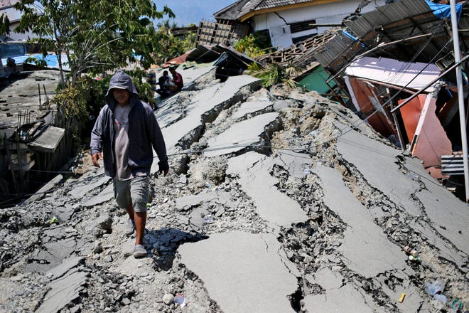 A man walks on a heavily damaged street due to the earthquake in Balaroa neighborhood in Palu, Central Sulawesi, Indonesia Indonesia, Tuesday, Oct. 2, 2018. Desperation was visible everywhere Tuesday among victims receiving little aid in areas heavily damaged by a massive earthquake and tsunami, four days after the disaster devastated parts of Indonesia's central Sulawesi island. (AP Photo/Dita Alangkara)