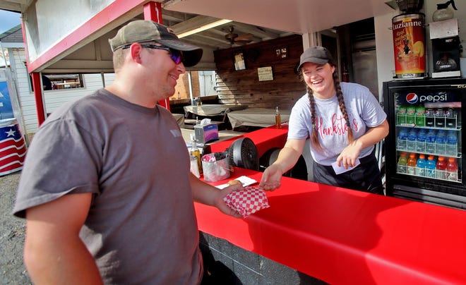 From left, Adam Bridges takes his burger from Nichole Fender at Hankster’s booth at the Cleveland County Fair on Friday. [Brittany Randolph/The Star]