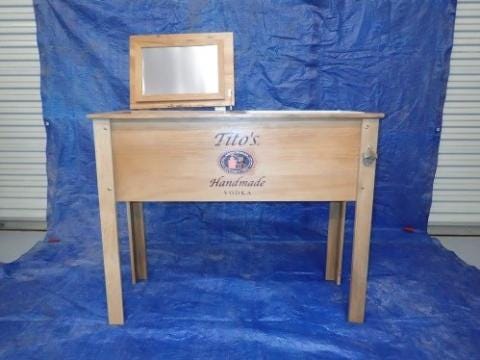 The cooler/grill units measures approximately 35 inches high 44 inches wide and 16 inches deep. The words “Tito's Handmade Vodka” are inscribed on the front of the product.