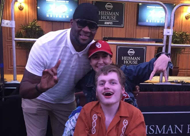 Vince Young, left, found time for a hug and a photo with Lisa Kinzer and her son Thomas at a recent Longhorn football game. [Michael J. Kinzer]