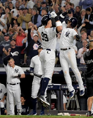 New York Yankees' Aaron Judge (99) celebrates with Andrew McCutchen after hitting a two-run home run against the Oakland Athletics during the first inning of the American League wild card game Wednesday in New York [Bill Kostroun/The Associated Press]