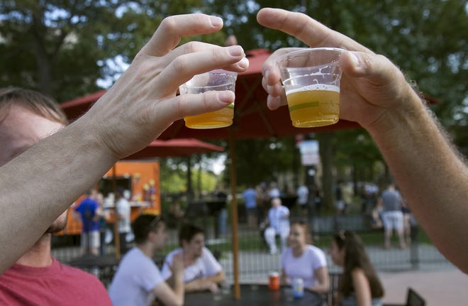 Bill Drinkwater of Millbury and Bruce Rioux of Douglas compare the colors of samples from Start Line Brewing in Hopkinton during last year's Mass Fermentational on Worcester Common. [T&G File/Michelle Sheppard]