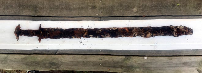 This photo taken in July 2018 and released by the Jonkopings lans Museum on Friday, Oct. 5 2018 shows a pre-Viking era sword in Jonkopings, Sweden. Mikael Nordstrom of the local Jonkoping County museum says 8-year-old Saga Vanecek was helping her father with his boat in the Vidostern lake when she stepped on an 85-centimeter (34-inch) sword in a holster made of wood and leather, believed to be about 1,500 years old. (Annie Rosen/Jonkopings lans Museum via AP)