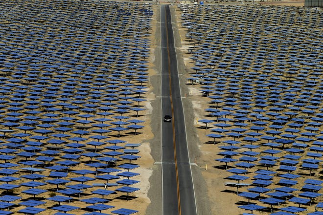 A car drives past some of the 347,000 garage door-sized mirrors awaiting the sun on opening day at the Ivanpah Solar Electric Generating System in the Ivanpah Valley near the California/Nevada in 2014. The 5.5-square mile plant in the Mojave Desert will generate 392 megawatts of power. [Mark Boster /Los Angeles Times file via TNS]