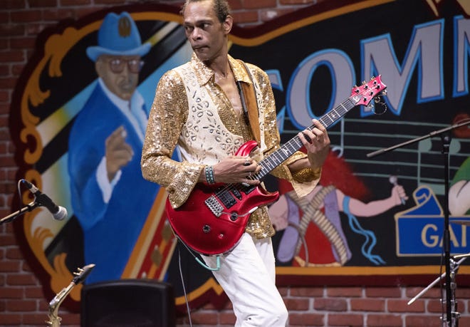 Guitarist Scott Free, who performed for years with Bo Diddley, whose likeness is shown at left in the backdrop mural at the Bo Diddley Plaza, says his favorite guitar riffs include siminal licks by Bo Diddley and Chuck Berry as well as a more recent tune by Aerosmith. [PHOTO BY SUZANNA MARS]