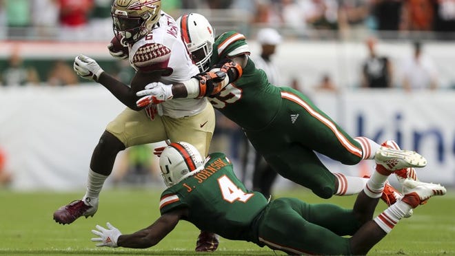 Florida State tight end Tre' McKitty (6) is stopped by Miami Hurricanes defensive back Jaquan Johnson (4) and defensive lineman Joe Jackson (99) after a first down during the first quarter at Hard Rock Stadium in Miami Gardens, Fla., on Saturday Oct. 6, 2018. Miami won, 28-27. (Monica Herndon/Tampa Bay Times/TNS)