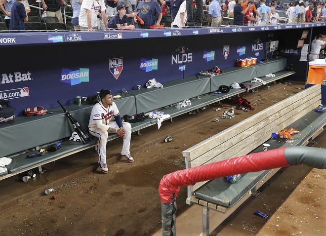 The Braves' Johan Camargo sits in the dugout alone, the last to leave, while watching the Los Angeles Dodgers celebrate a victory in Game 4 of their National League Division Series on Monday in Atlanta. [CURTIS COMPTON/ATLANTA JOURNAL-CONSTITUTION VIA AP]
