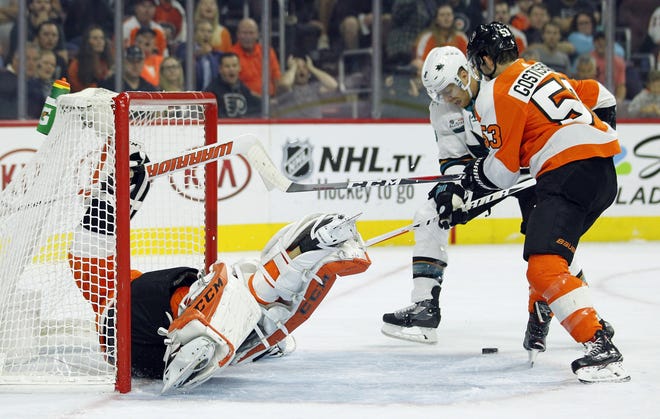 Flyers goalie Brian Elliott sprawls in the net after a goal by Evander Kane, not pictured, while the Sharks' Joe Pavelski and the Flyers' Shayne Gostisbehere vie for the loose puck Tuesday. [TOM MIHALEK/ASSOCIATED PRESS]